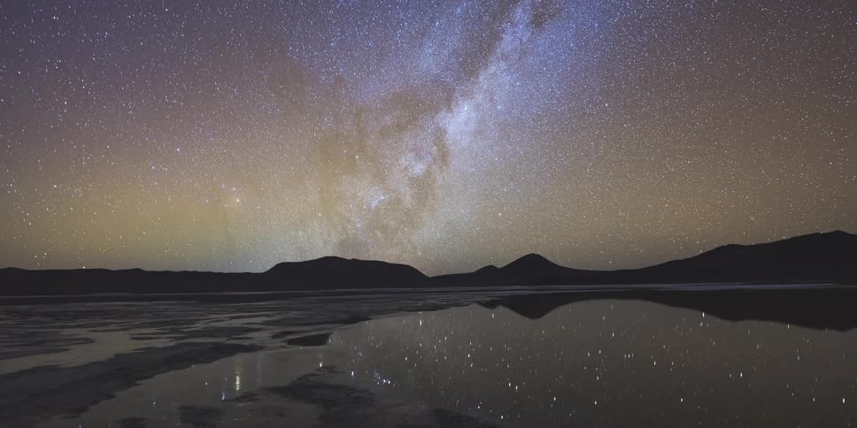 The stars in the sky reflect on the lake water