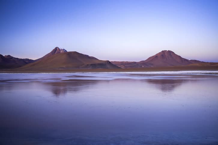 Mountains reflected in a calm lake under a deep blue sky