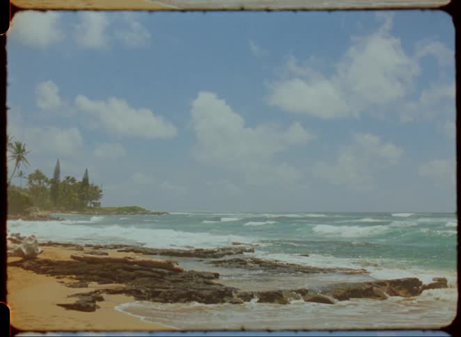 Waves breaking at a beach surrounded by rocks and vegetation outdoors during day time