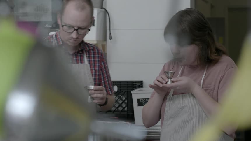 A man and woman both sip out of tiny cups