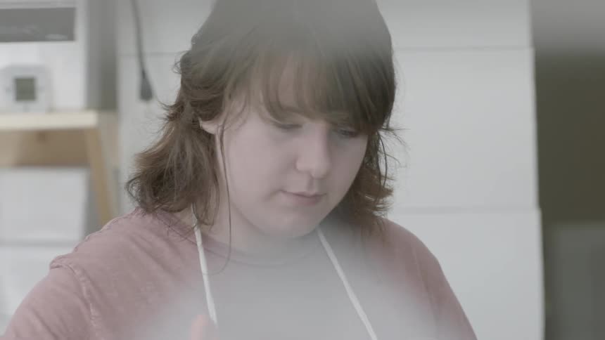 A woman is mixing something in a kitchen