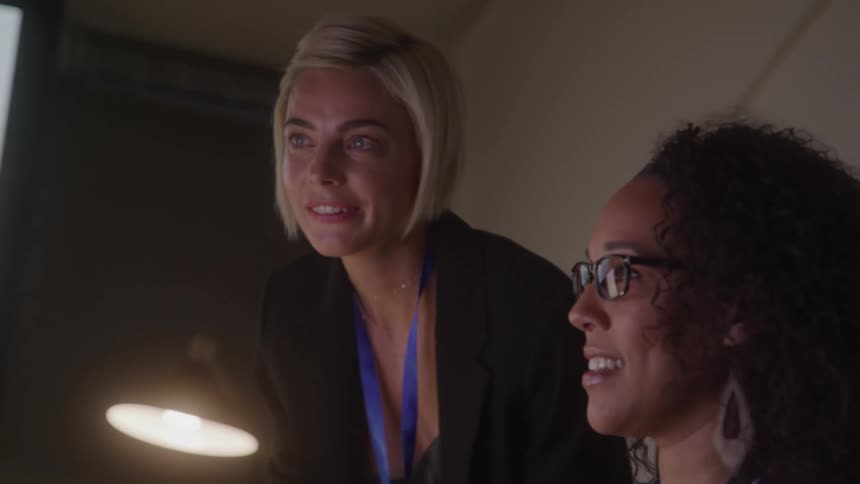 Two women talk and point at the monitor in the office