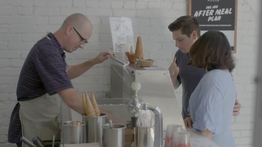 A man and woman taste samples in an ice cream parlor