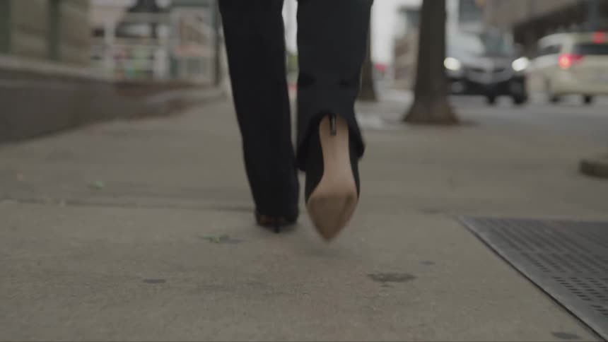 The woman walks on the sidewalk in the city