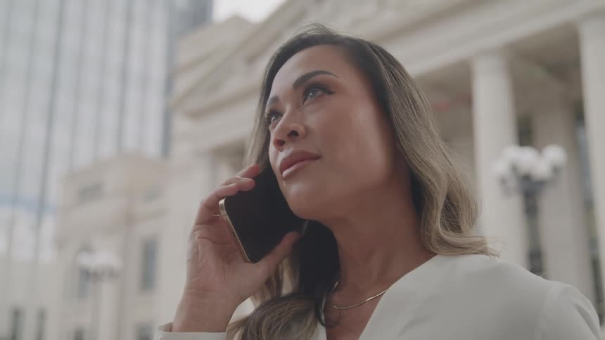 The woman listens on her cell phone by the buildings