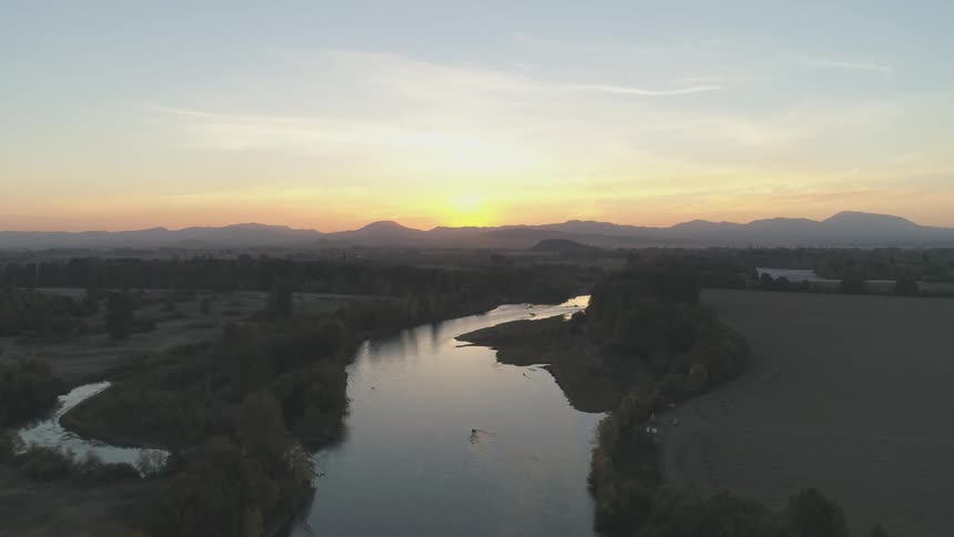 A large river surrounded by land under a sky in sunrise