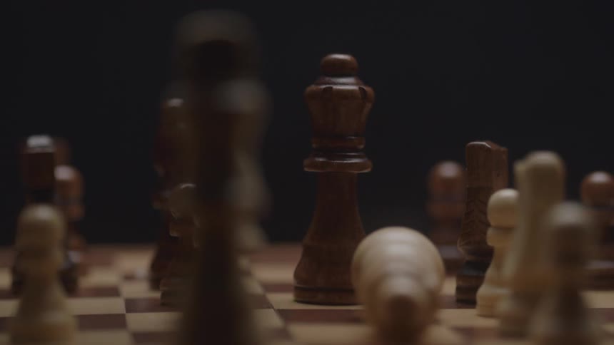 The person pushes the piece during a chess game