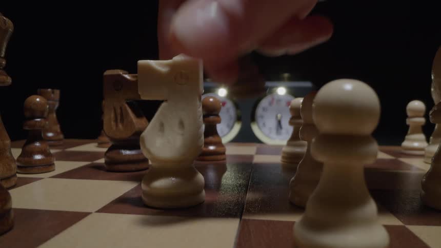 Male hands moving a chess piece and ticking the chess clock indoors
