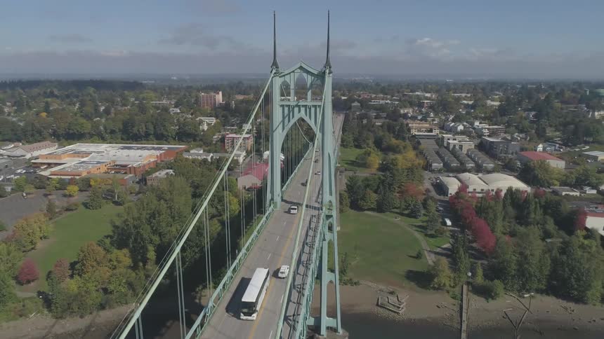 Different types of vehicles crossing a bridge over a river next to a city