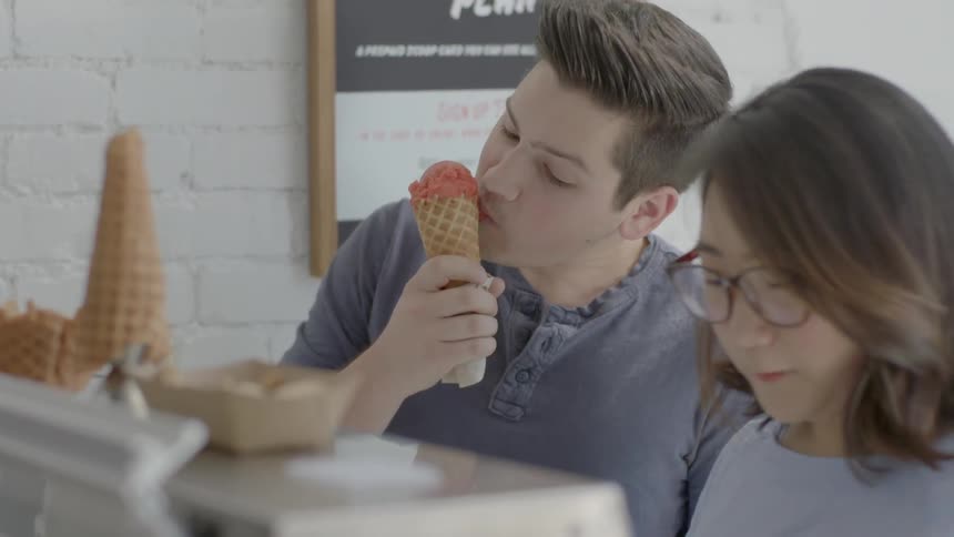 A woman takes a taste of her male companion's ice-cream