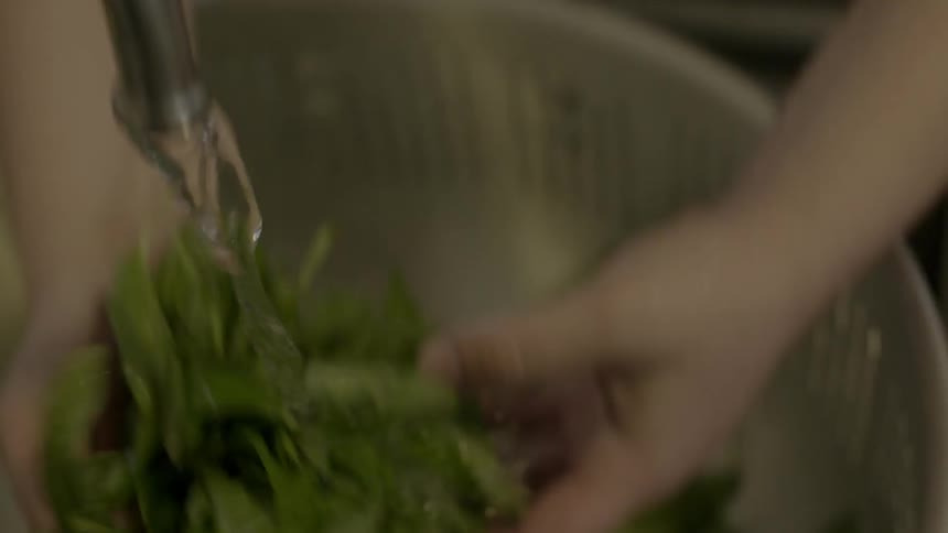 A woman looks down cleaning some vegetables