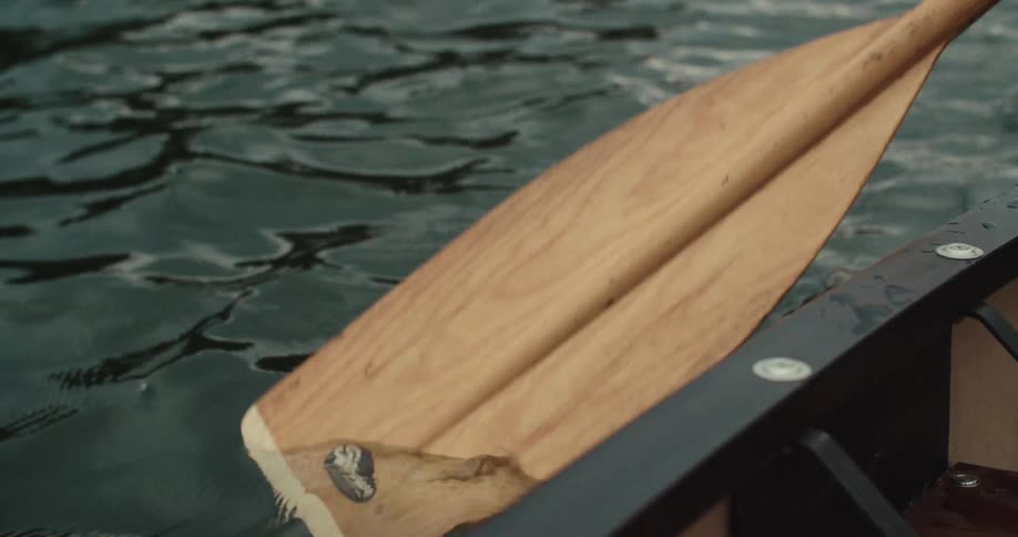 Boat oar cuts through the water near the rowboat during the daytime