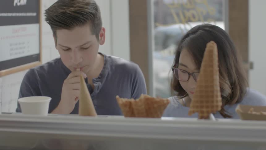 Two people taste ice cream in a shop