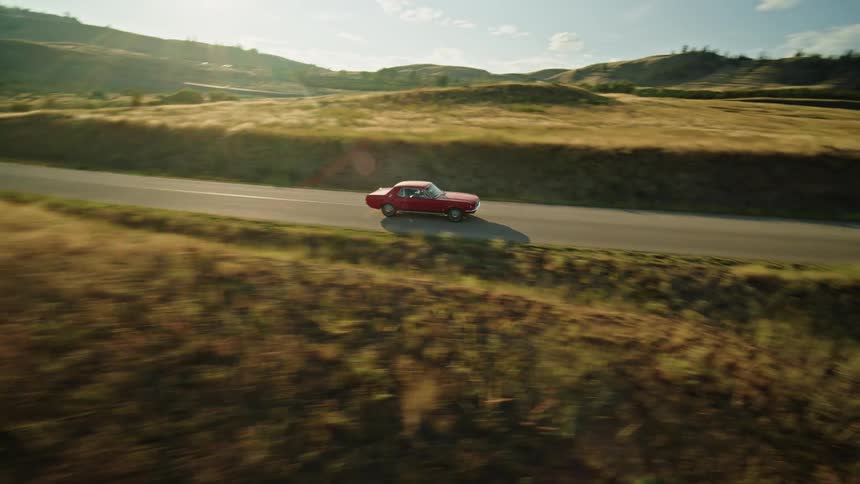 The video filmed from a moving vehicle shows two distinct lines the first line is the road a twolane asphalt path that curves through rolling grassy hills the second line is the horizon where a large blue lake meets the base of the mountai