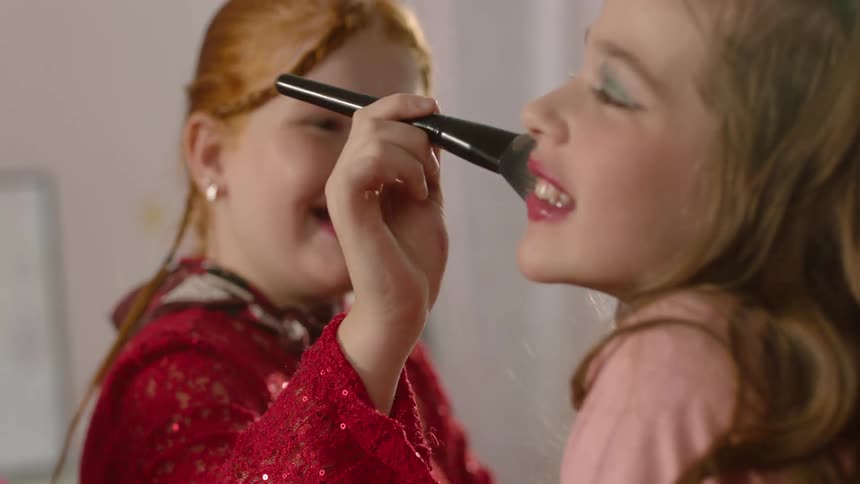 The girl applies makeup to a friends face