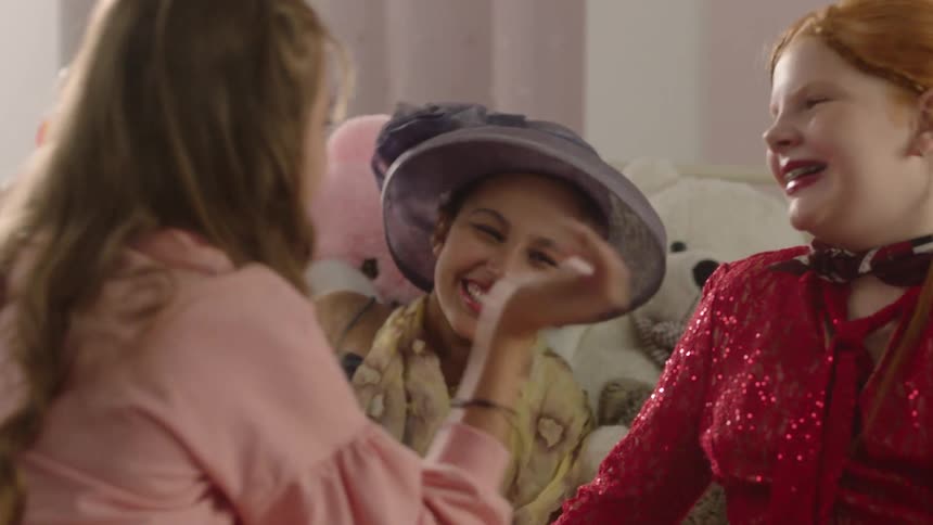 Girls are happily playing dress up and putting on makeup together