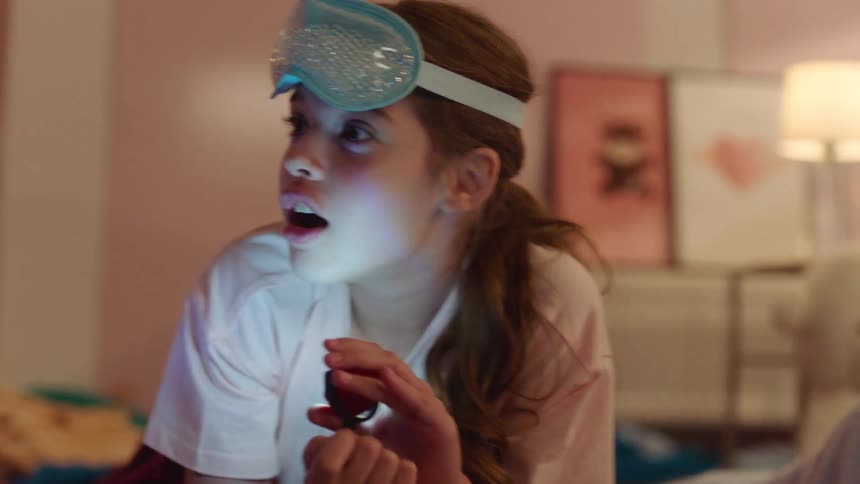 Three girls playing in a bedroom telling stories to each other and all holding a flashlight