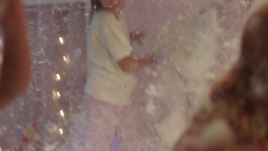 Four girls having a pillow fight in a bedroom setting