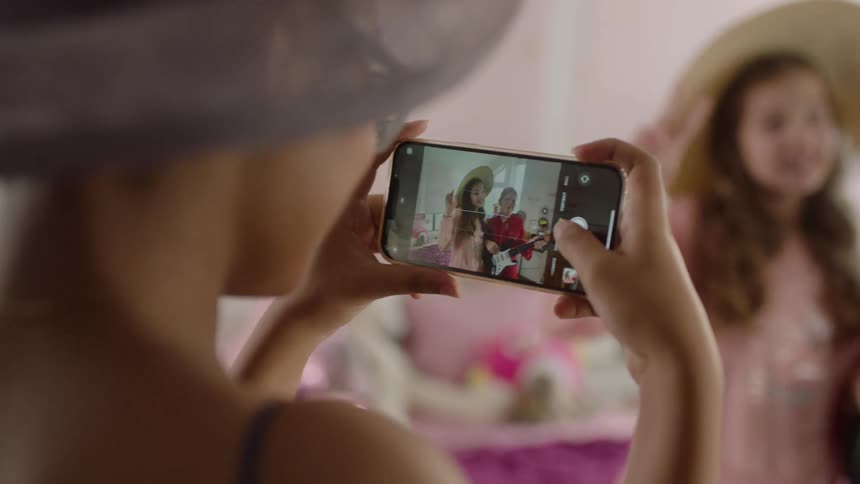 Kids pose for a photo as another takes it with a smartphone
