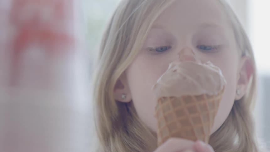 A child eats ice cream and gets it on her nose