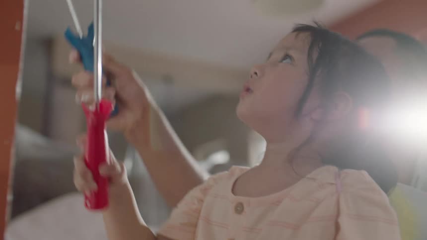 Father and daughter painting the wall of their house with a roller
