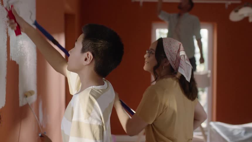 A family paints the walls of a room together with brushes and rollers