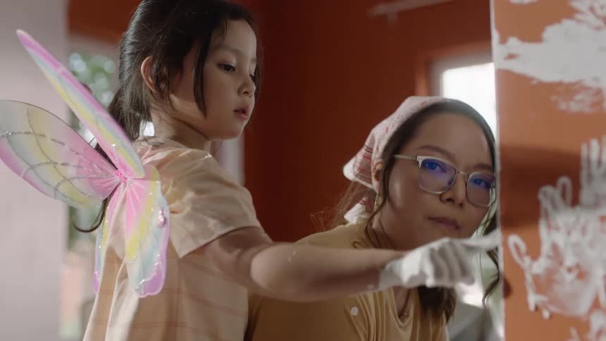 Little girl with her hand full of paint rubbing it on her mother