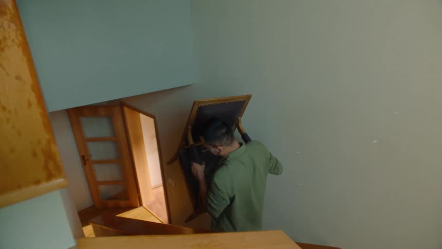 The man carries the chair down the stairs