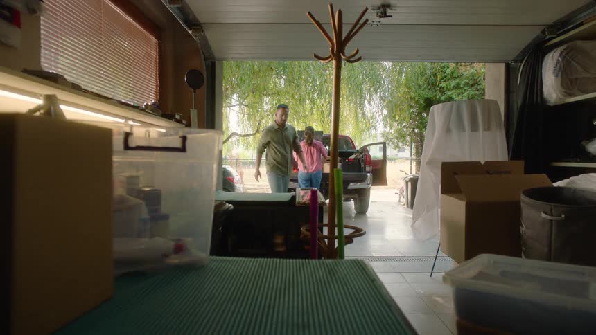 Man and a woman taking items out of a garage and putting them into a pickup truck