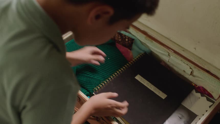 A boy goes through a red suitcase taking out a toy airplane and then a photo book to look through the pictures