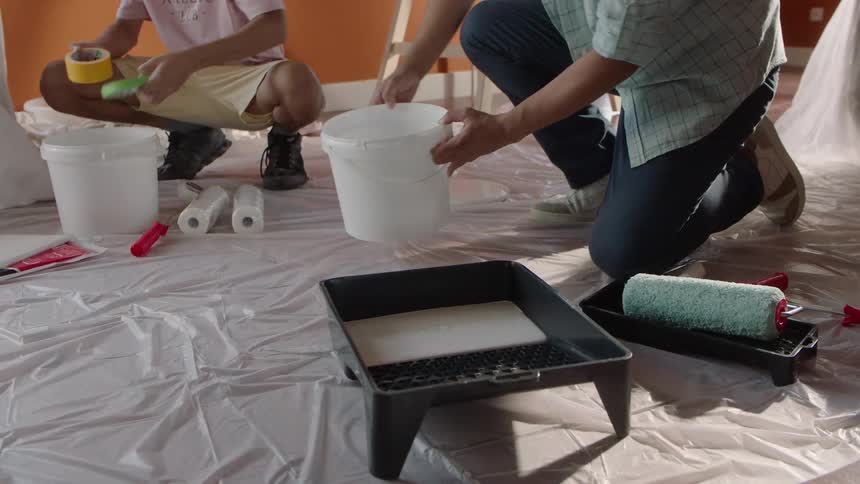 Father and son prepare to renovate a room with paint and roller