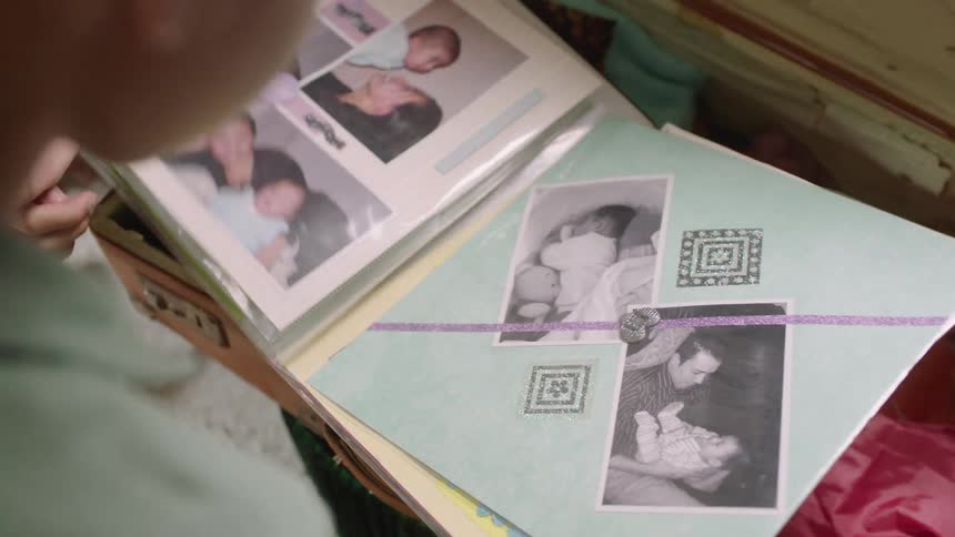 A young boy looks through a photo book indoors at midday