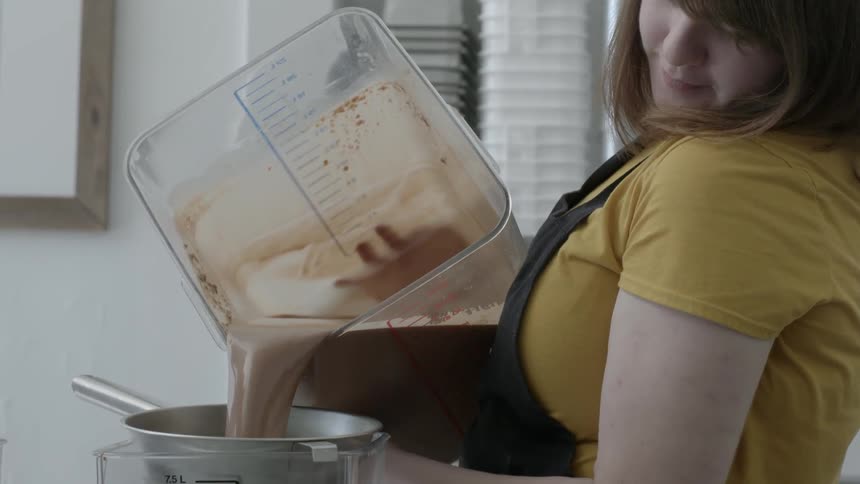 A woman pours ingredients into a strainer