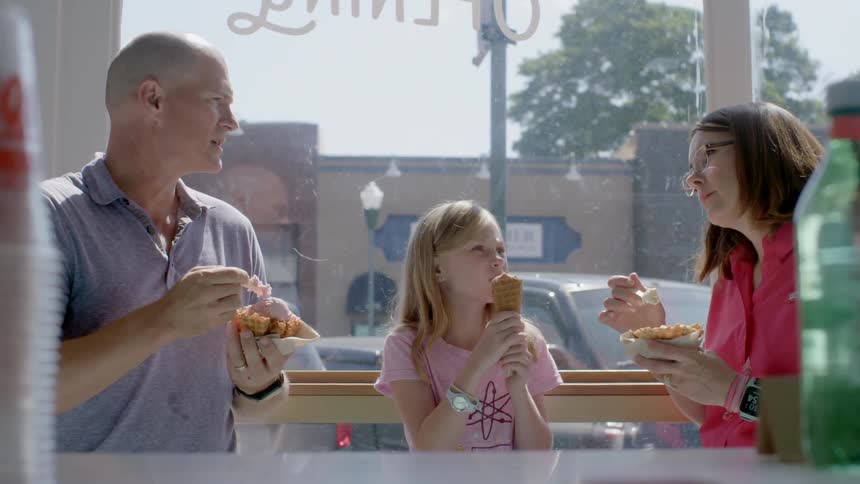 A man, woman and child eat ice cream in a shop