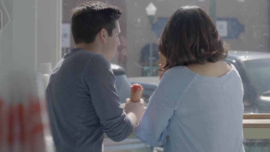 A man and woman are eating ice-cream in an ice-cream parlor