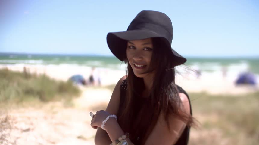 A woman wearing  a black hat puts her hand to her face and turns around