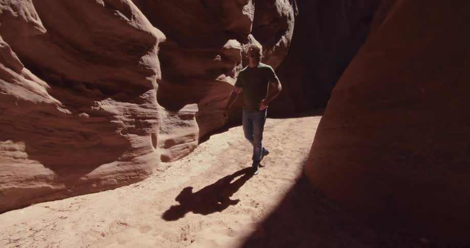 Man walking along a trail between rocks with natural erosion