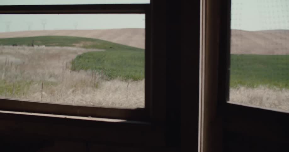 Man in a hat in a field seen through a window