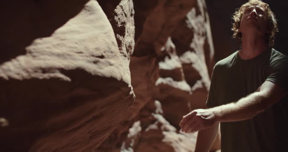 The video shows a man touching a large rock formation two lines are visible the natural edge of the rock itself which is a jagged and uneven vertical line and a sharp diagonal shadow line on the rocks surface separating the illuminated and
