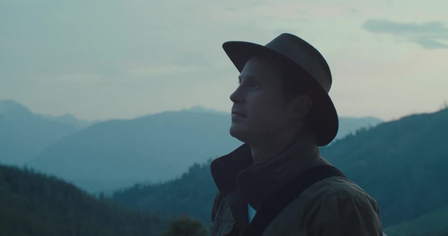 Man in hat walking through the mountains at sunrise