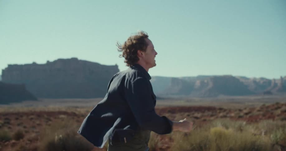 The man turns around while running in the desert