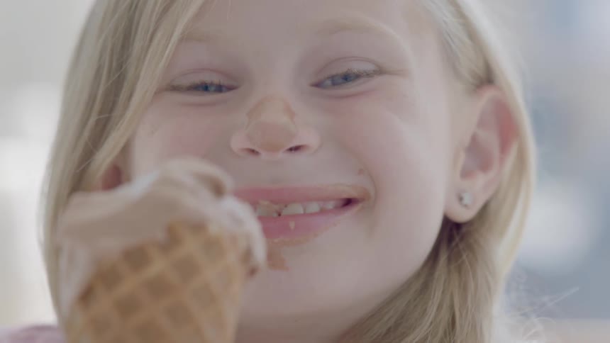 A young girl eats ice cream from a cone