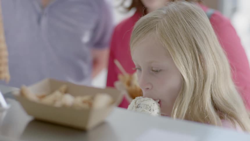 A person puts ice-cream into a cone and hands it to a customer