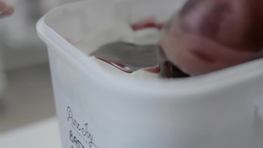 A sauce is ladled into a container container an ice-cream mixture