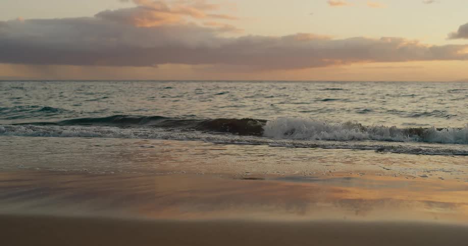Gentle waves break on the sand during sunset