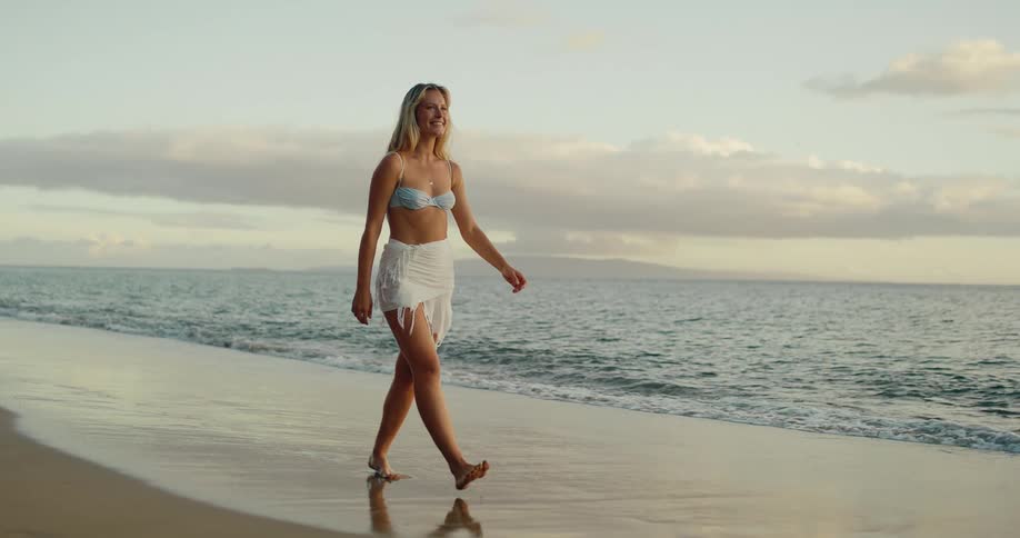 Smiling blonde woman walking on the beach