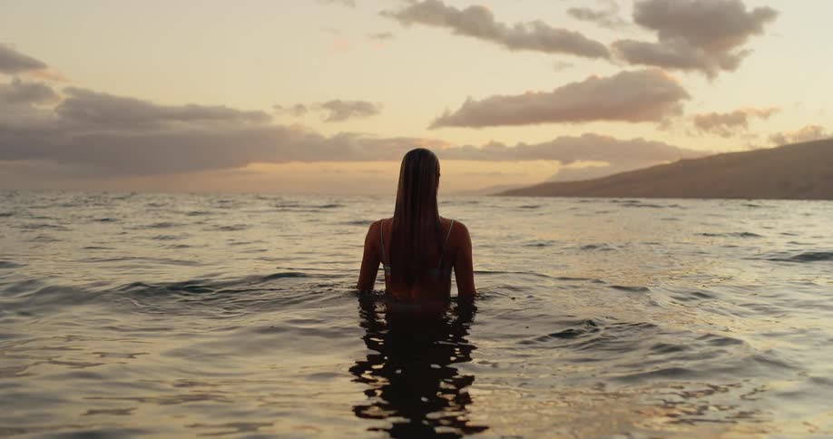 Woman in a calm sea at the end of the afternoon
