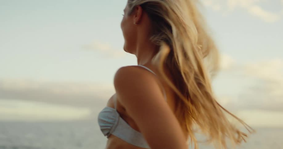 Woman in shorts and bikini running on the beach smiling