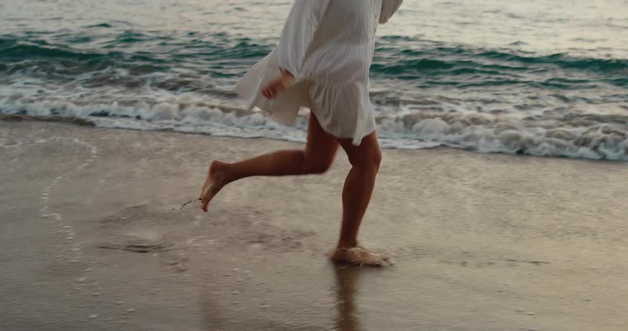 The woman smiles as she runs on the beach