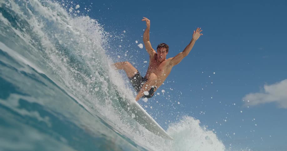 A man stands on a surfboard and rides on the face of a wave